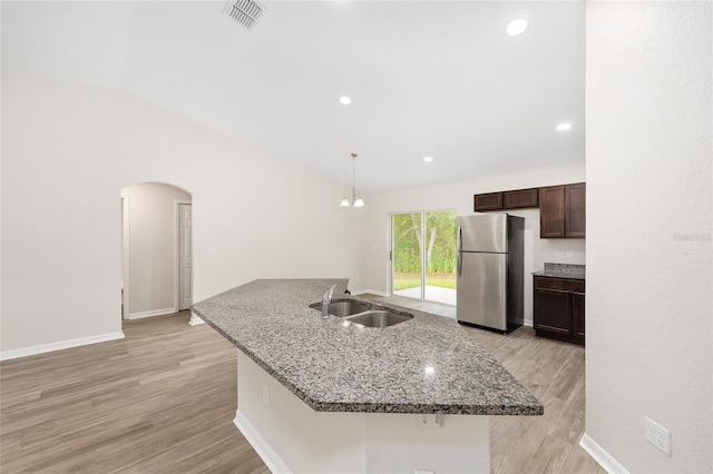 5 Water Pass, Ocala, FL 34472 - kitchen featuring freestanding refrigerator, vaulted ceiling, dark brown cabinetry, arched walkways, and light wood-style flooring