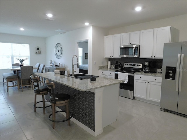 80 Hickory Course Loop, Ocala, FL 34472 - kitchen with stainless steel appliances, light stone countertops, an island with sink, white cabinetry, and recessed lighting