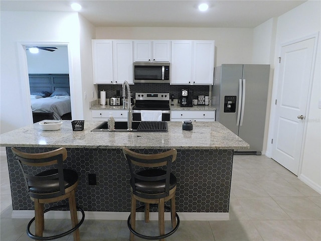 80 Hickory Course Loop, Ocala, FL 34472 - kitchen featuring appliances with stainless steel finishes, a center island with sink, white cabinets, and light stone counters