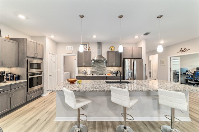 8913 SW 76th Ln, Ocala, FL 34481 - kitchen with stainless steel appliances, wall chimney range hood, light wood-type flooring, decorative backsplash, and washer and dryer