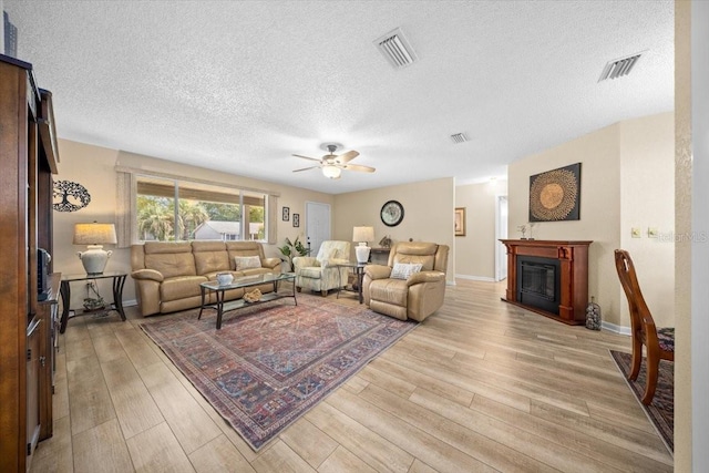 8461 SW 109th St, Ocala, FL 34481 - living room featuring a ceiling fan, a textured ceiling, light wood finished floors, and a glass covered fireplace