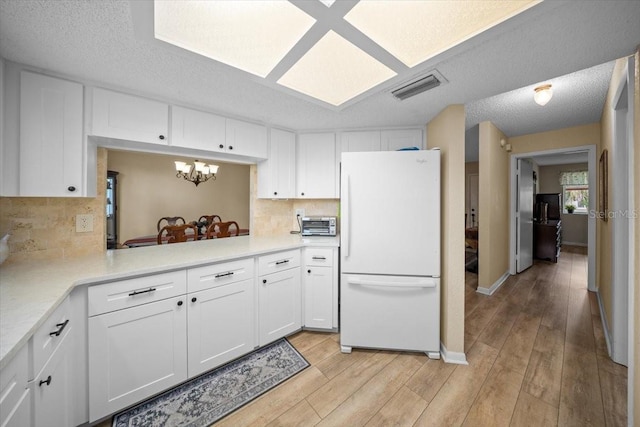 8461 SW 109th St, Ocala, FL 34481 - kitchen with freestanding refrigerator, light wood-style flooring, white cabinetry, and a textured ceiling