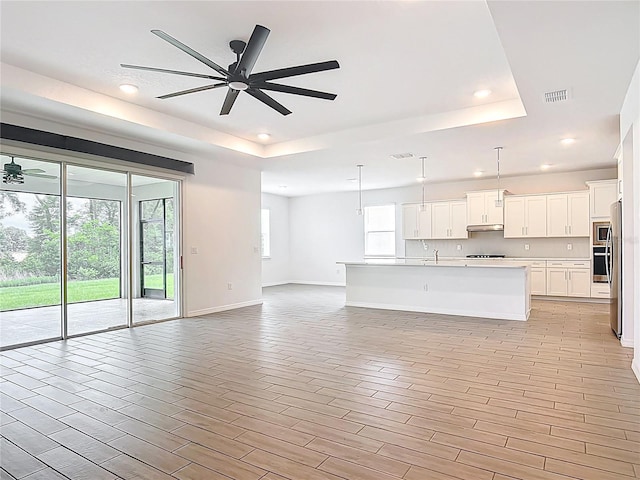 7067 SW 60th Ln, Ocala, FL 34474 - unfurnished living room with a tray ceiling, ceiling fan, recessed lighting, and light wood-style floors