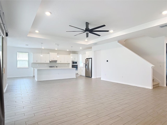 7067 SW 60th Ln, Ocala, FL 34474 - unfurnished living room with a raised ceiling, recessed lighting, ceiling fan, stairway, and light wood-type flooring