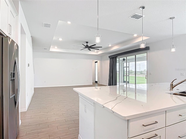 7067 SW 60th Ln, Ocala, FL 34474 - kitchen with stainless steel fridge, a tray ceiling, a ceiling fan, open floor plan, and white cabinets