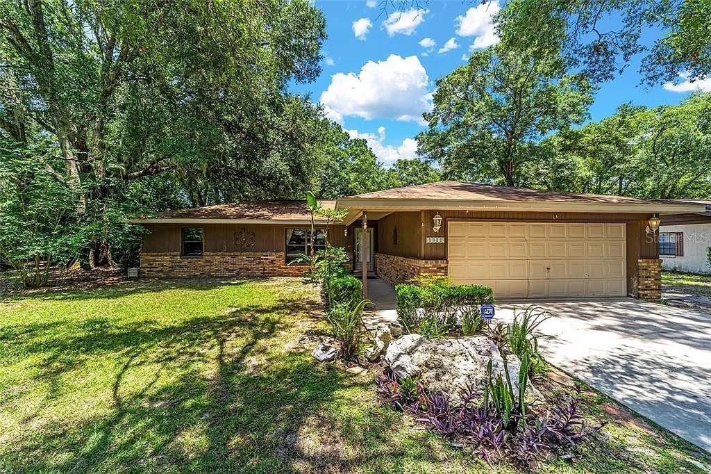 10615 SW 68th Ter, Ocala, FL 34476 - ranch-style home featuring an attached garage, concrete driveway, a front yard, and stone siding