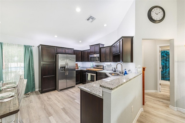 6 Sequoia Loop, Ocklawaha, FL 32179 - kitchen with appliances with stainless steel finishes, light stone countertops, dark brown cabinets, a peninsula, and light wood finished floors