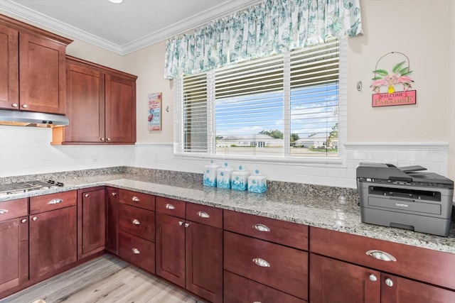 9926 SW 95th Loop, Ocala, FL 34481 - kitchen with under cabinet range hood, stainless steel gas cooktop, crown molding, light wood-style flooring, and light stone countertops