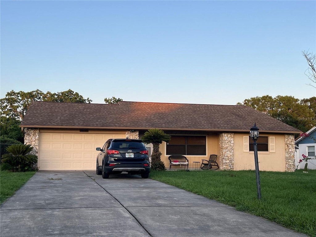 10885 SE 74th Ct, Belleview, FL 34420 - ranch-style home featuring concrete driveway, a garage, stone siding, a front lawn, and a shingled roof