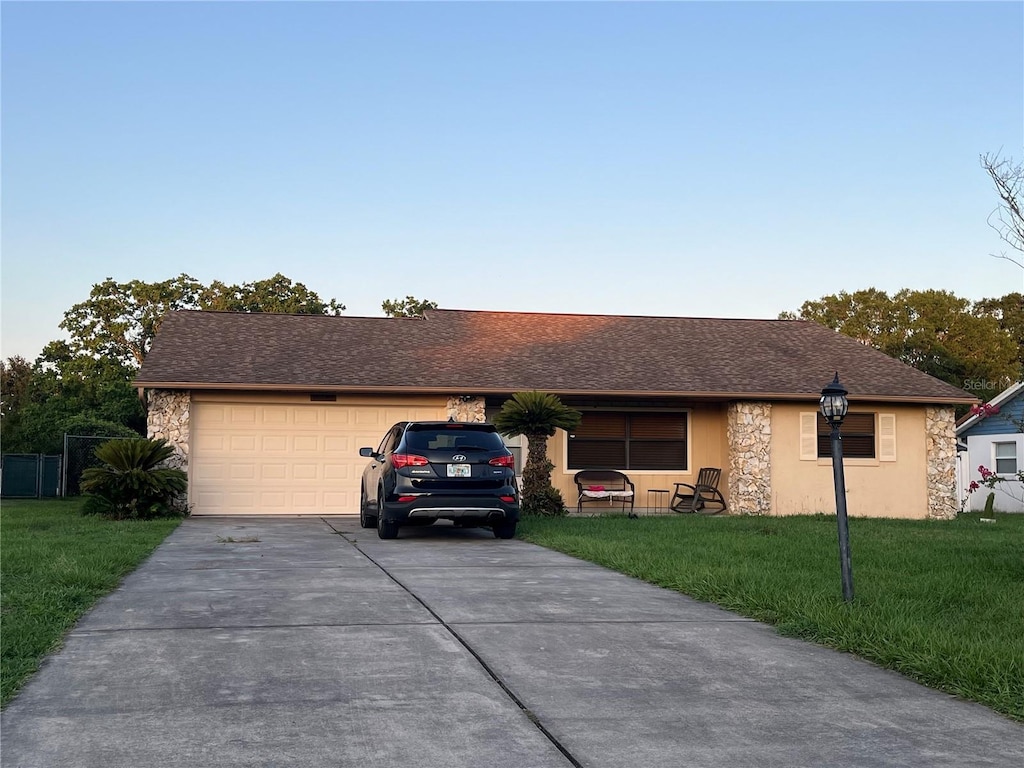 10885 SE 74th Ct, Belleview, FL 34420 - single story home with driveway, a front lawn, an attached garage, and stone siding