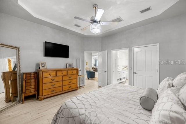 2418 SE 22nd Pl, Ocala, FL 34471 - bedroom with a raised ceiling, wood finished floors, a ceiling fan, and ensuite bathroom
