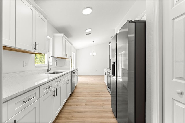 14876 SE 34th Ter, Summerfield, FL 34491 - kitchen featuring appliances with stainless steel finishes, white cabinetry, light wood-style floors, pendant lighting, and light stone counters