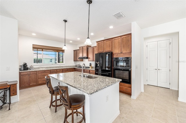 9222 SW 97th Cir, Ocala, FL 34481 - kitchen with black appliances, brown cabinets, light stone counters, recessed lighting, and a kitchen island with sink