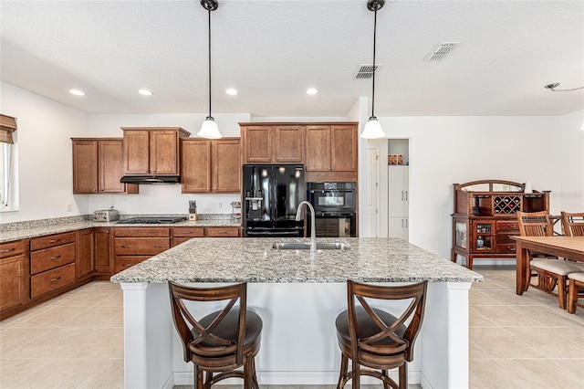 9222 SW 97th Cir, Ocala, FL 34481 - kitchen featuring black appliances, brown cabinetry, under cabinet range hood, light stone countertops, and a textured ceiling