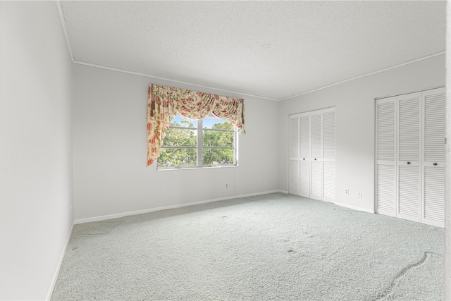 8830 SW 98th Pl Unit M, Ocala, FL 34481 - unfurnished bedroom featuring carpet floors, multiple closets, ornamental molding, and a textured ceiling