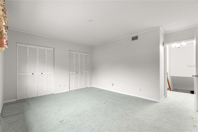 8830 SW 98th Pl Unit M, Ocala, FL 34481 - unfurnished bedroom with multiple closets, carpet floors, crown molding, and a chandelier