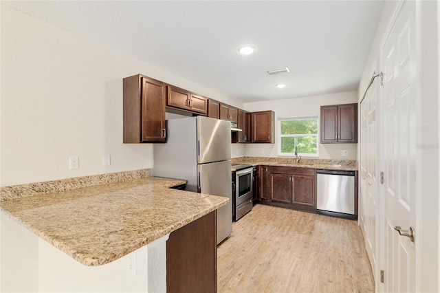 2139 NE 78th Ln, Ocala, FL 34479 - kitchen with appliances with stainless steel finishes, a peninsula, light wood-type flooring, dark brown cabinets, and recessed lighting