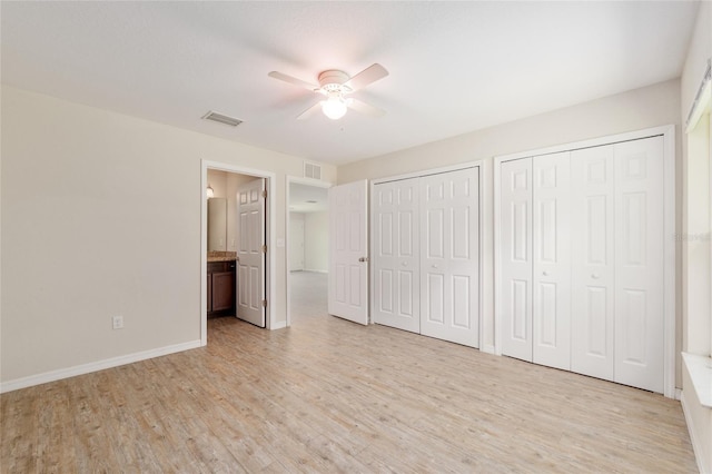 2139 NE 78th Ln, Ocala, FL 34479 - unfurnished bedroom featuring two closets, light wood-style floors, ceiling fan, and ensuite bath