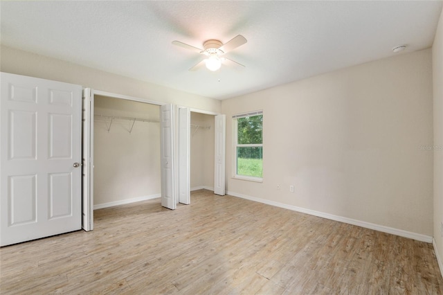 2139 NE 78th Ln, Ocala, FL 34479 - unfurnished bedroom featuring two closets, light wood finished floors, and a ceiling fan