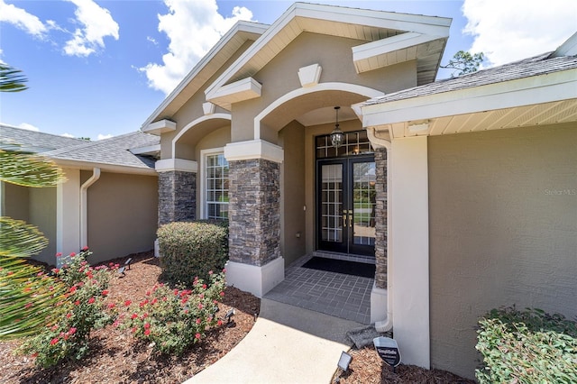 2908 SE 22nd Ave, Ocala, FL 34471 - view of exterior entry with stucco siding, stone siding, roof with shingles, and french doors