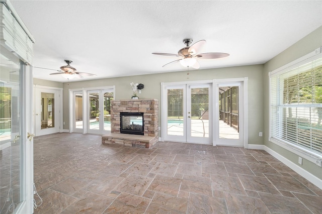 2908 SE 22nd Ave, Ocala, FL 34471 - unfurnished living room featuring ceiling fan, french doors, stone tile floors, and a stone fireplace