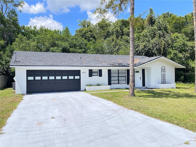 21111 SW Honeysuckle St, Dunnellon, FL 34431 - view of front of property with a garage, driveway, a front lawn, and stucco siding