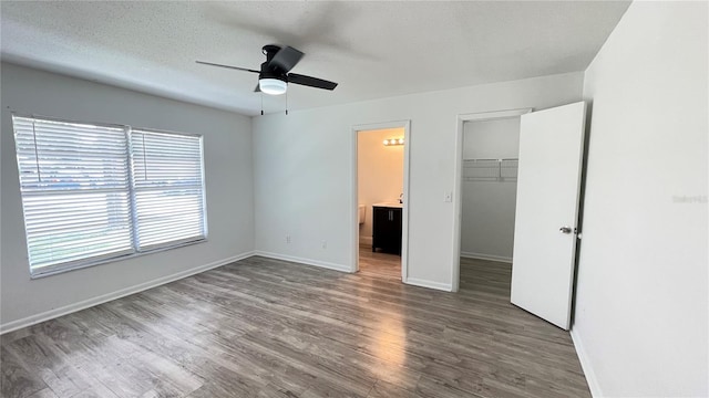 21111 SW Honeysuckle St, Dunnellon, FL 34431 - unfurnished bedroom featuring wood finished floors, a spacious closet, a closet, a ceiling fan, and connected bathroom