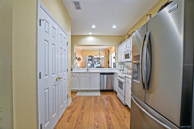 13170 SE 92nd Court Rd, Summerfield, FL 34491 - kitchen featuring stainless steel appliances, white cabinetry, light countertops, light wood-style floors, and recessed lighting