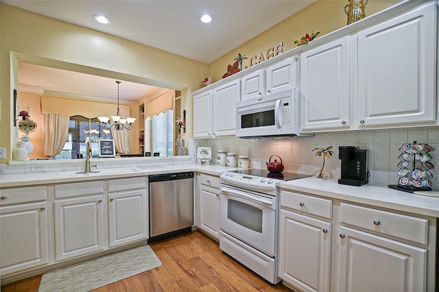 13170 SE 92nd Court Rd, Summerfield, FL 34491 - kitchen with white appliances, a chandelier, white cabinets, backsplash, and recessed lighting