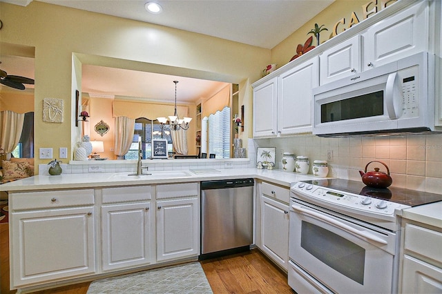 13170 SE 92nd Court Rd, Summerfield, FL 34491 - kitchen featuring white appliances, a chandelier, white cabinetry, decorative backsplash, and light countertops