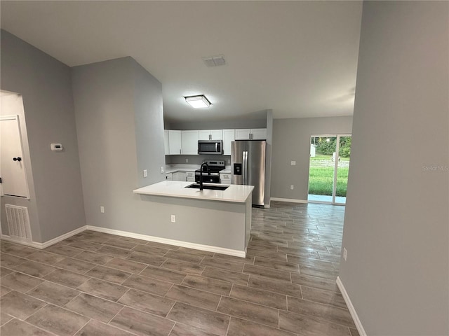 5 Laurel Pass Ln, Ocala, FL 34472 - kitchen featuring appliances with stainless steel finishes, white cabinetry, light countertops, a peninsula, and wood finished floors