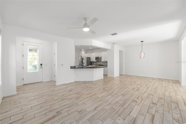 4970 NW 35th Lane Rd, Ocala, FL 34482 - kitchen with stainless steel appliances, open floor plan, dark countertops, a peninsula, and white cabinetry