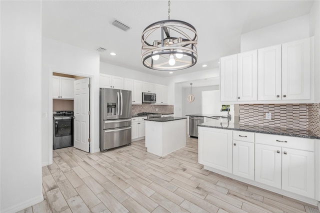 4970 NW 35th Lane Rd, Ocala, FL 34482 - kitchen with stainless steel appliances, tasteful backsplash, a chandelier, white cabinetry, and pendant lighting