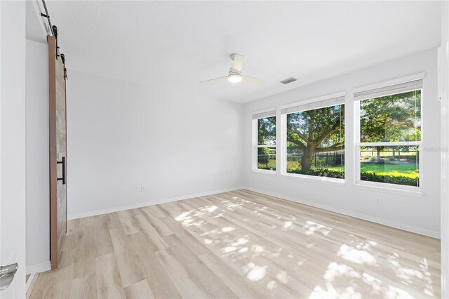 4970 NW 35th Lane Rd, Ocala, FL 34482 - empty room with a barn door, light wood finished floors, and ceiling fan
