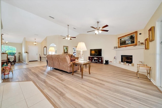 5459 SW 86th St, Ocala, FL 34476 - living area with a fireplace with raised hearth, light wood-type flooring, vaulted ceiling, a ceiling fan, and a chandelier