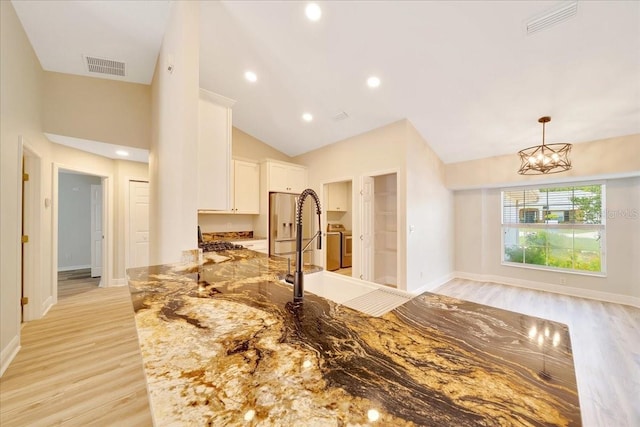 6631 SE 11th Loop, Ocala, FL 34472 - kitchen featuring light stone countertops, white cabinetry, vaulted ceiling, light wood-style flooring, and a chandelier