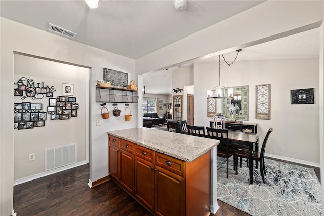 501 Marion Oaks Dr, Ocala, FL 34473 - kitchen with dark wood-type flooring, brown cabinetry, light stone countertops, and hanging light fixtures