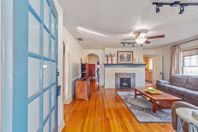 114 NE 11th Ave, Ocala, FL 34470 - living area with arched walkways, a ceiling fan, light wood finished floors, a fireplace, and a textured ceiling