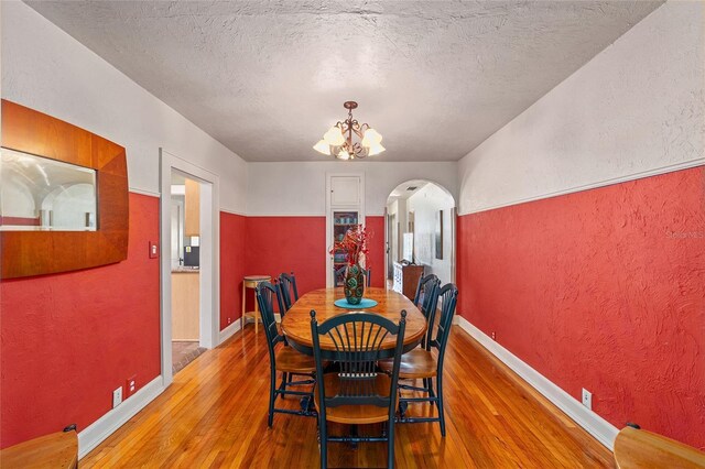 114 NE 11th Ave, Ocala, FL 34470 - dining room featuring arched walkways, a textured wall, wood finished floors, a chandelier, and a textured ceiling