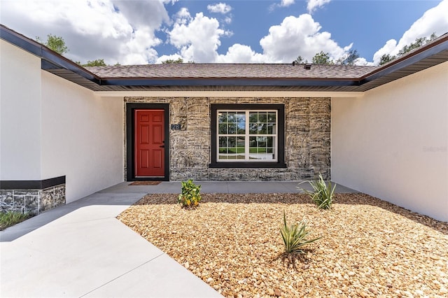 28 Water Track Dr, Ocala, FL 34472 - view of exterior entry featuring stone siding, a porch, stucco siding, and a shingled roof