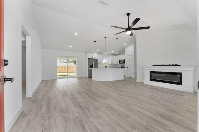 28 Water Track Dr, Ocala, FL 34472 - unfurnished living room featuring vaulted ceiling, ceiling fan, light wood-type flooring, recessed lighting, and a glass covered fireplace