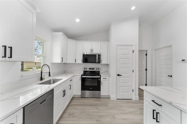 28 Water Track Dr, Ocala, FL 34472 - kitchen featuring stainless steel appliances, white cabinetry, light stone counters, vaulted ceiling, and light wood-style flooring