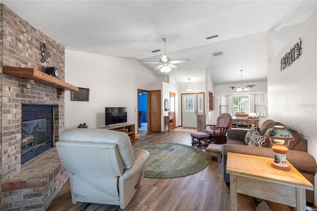 7443 SW 102nd Pl, Ocala, FL 34476 - living room featuring lofted ceiling, a fireplace, a ceiling fan, wood finished floors, and a textured ceiling