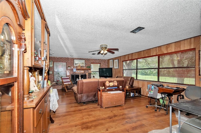 2676 SE 52nd Ave, Ocala, FL 34480 - living area featuring a ceiling fan, a textured ceiling, light wood-style flooring, brick wall, and wooden walls