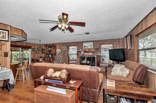 2676 SE 52nd Ave, Ocala, FL 34480 - living room with a ceiling fan, a textured ceiling, wood walls, wood finished floors, and brick wall