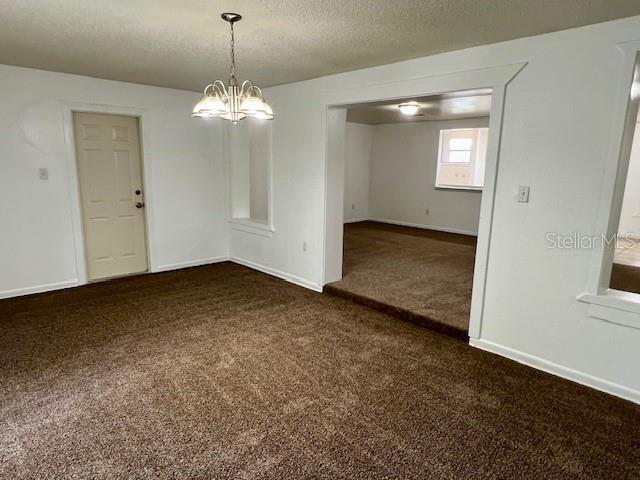 3801 SW 147th Lane Rd, Ocala, FL 34473 - empty room with dark colored carpet, a textured ceiling, and a chandelier