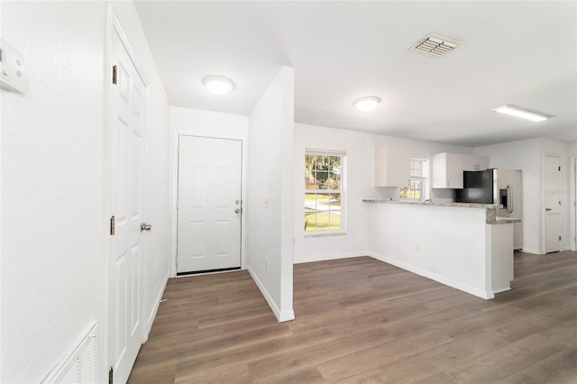 5596 NW 57th St, Ocala, FL 34482 - kitchen featuring stainless steel fridge, a peninsula, wood finished floors, light countertops, and white cabinetry