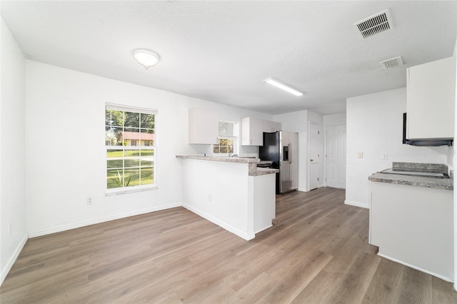 5596 NW 57th St, Ocala, FL 34482 - kitchen featuring stainless steel refrigerator with ice dispenser, a peninsula, light wood-style flooring, light countertops, and white cabinets