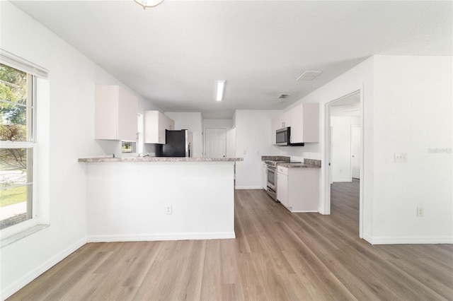 5596 NW 57th St, Ocala, FL 34482 - kitchen with appliances with stainless steel finishes, light wood-style flooring, white cabinetry, and a peninsula