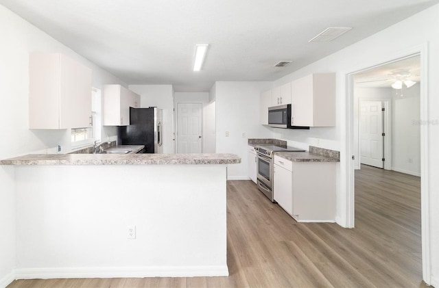 5596 NW 57th St, Ocala, FL 34482 - kitchen with stainless steel appliances, a peninsula, light wood-style floors, white cabinets, and light countertops
